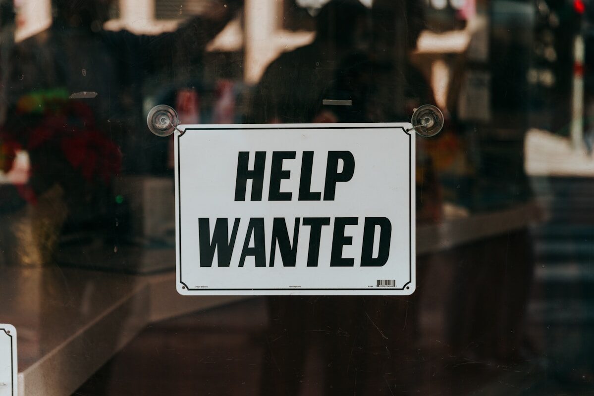 Job Listing a sign that says help wanted on a glass door