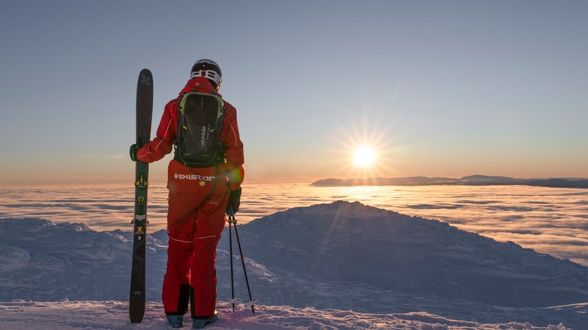 Backcountry a man holding skis standing on top of a snow covered slope
