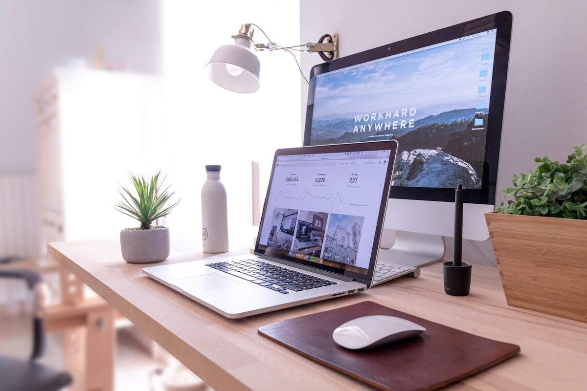 Web Design MacBook Pro on table beside white iMac and Magic Mouse