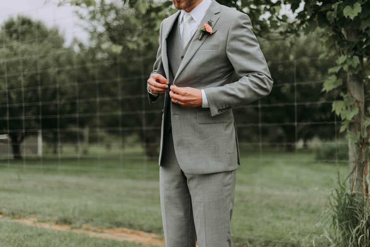 Suit standing man holding his notched lapel suit jacket's button