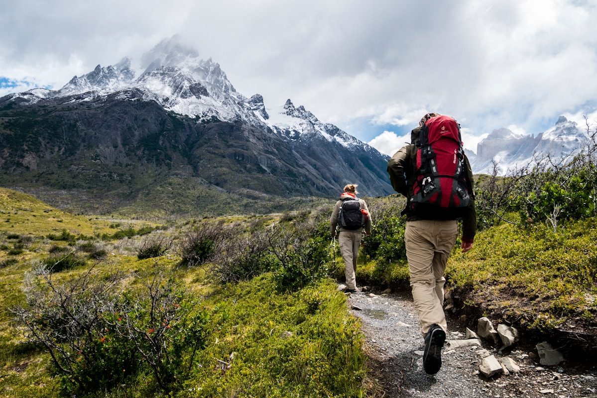 Hikers Two hikers with backpacks walking along a trail toward snow-capped mountains